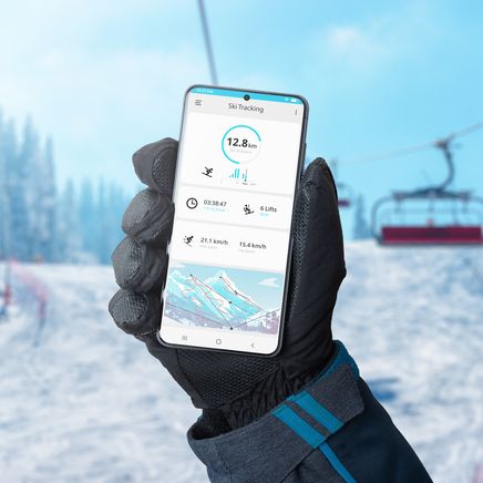 Un skieur tenant dans sa main un smarthphone équipé d'un GPS pour le ski
